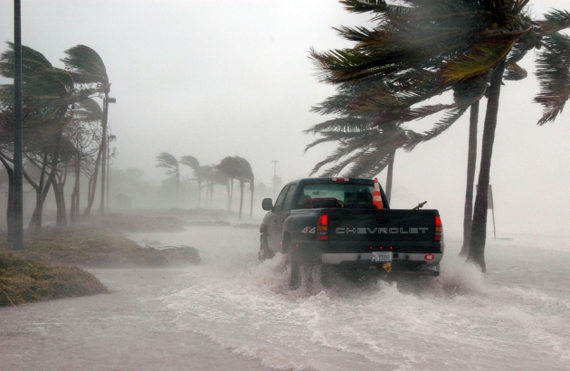 A truck driving through a water filled street in a hurricane.